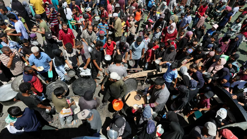 Palestinians gather to receive food from a charity kitchen, amid a hunger crisis, in Nuseirat, central Gaza Strip, July 20, 2025. REUTERS/Ramadan Abed