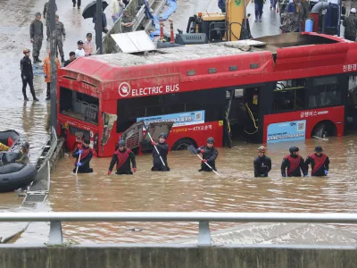 Rescuers search for survivors along a road submerged by floodwaters leading to an underground tunnel in Cheongju, South Korea, Sunday, July 16, 2023. Days of heavy rain triggered flash floods and landslides and destroyed homes, leaving scores of people dead and forcing thousands to evacuate, officials said Sunday. (Kim Ju-hyung/Yonhap via AP)