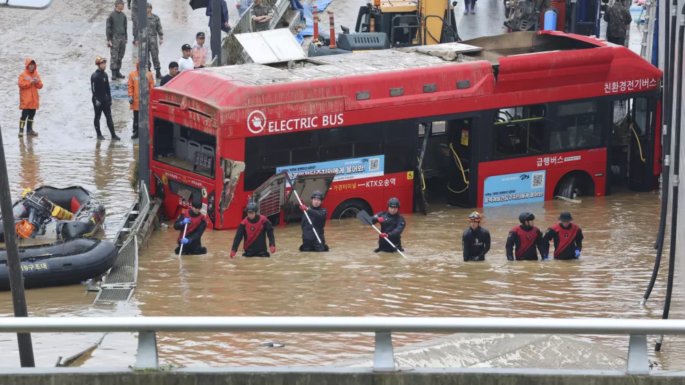 Rescuers search for survivors along a road submerged by floodwaters leading to an underground tunnel in Cheongju, South Korea, Sunday, July 16, 2023. Days of heavy rain triggered flash floods and landslides and destroyed homes, leaving scores of people dead and forcing thousands to evacuate, officials said Sunday. (Kim Ju-hyung/Yonhap via AP)