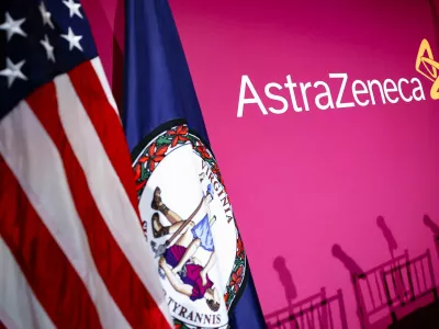 The flags of the U.S. and the state of Virginia stand next to the AstraZeneca logo during a signing event for documents related to a manufacturing site investment at the Meridian International Center in Washington, D.C., July 21, 2025. REUTERS/Umit Bektas