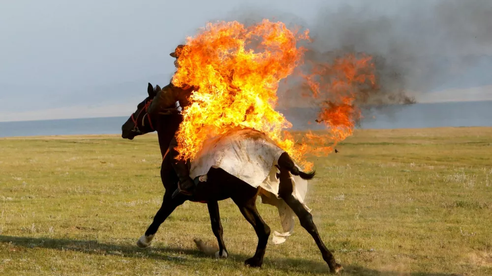 A horseback rider performs a fire stunt during a show organized for the participants of the "Gallops" orienteering and endurance equestrian race, involving international teams of 5 or 6 members, near Lake Song Kol in an alpine valley in the Naryn region, Kyrgyzstan, July 21, 2025. REUTERS/Vladimir Pirogov   TPX IMAGES OF THE DAY / Foto: Vladimir Pirogov