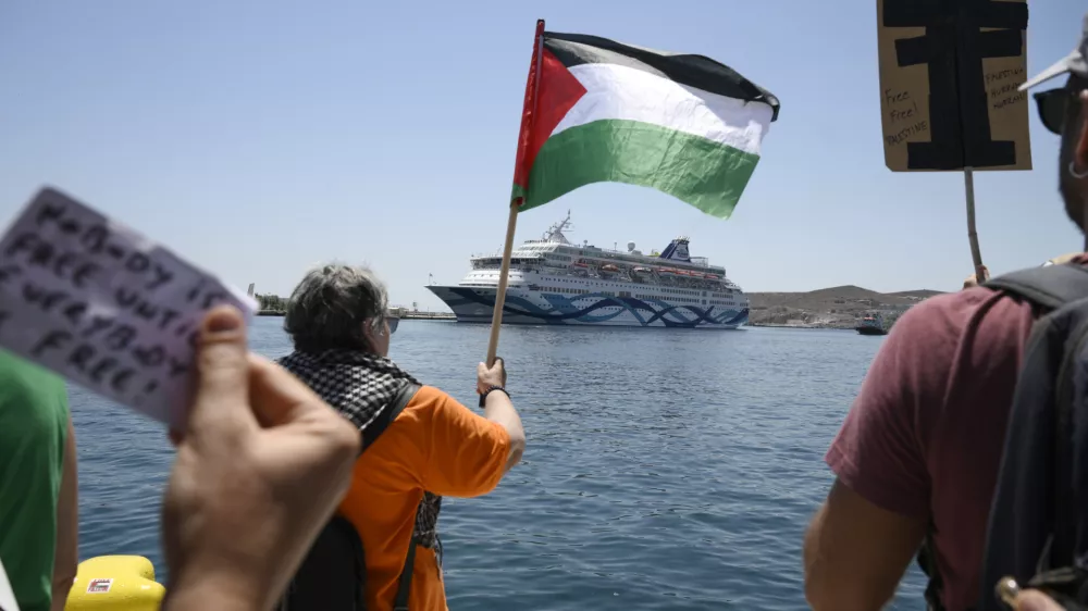 A protester waves a Palestinian flag as people demonstrates in front of a cruise ship carrying Israeli tourists and trying to approach the Aegean Sea island of Syros, Greece, Tuesday, July 22, 2025. (Nikos Panagiotopoulos/InTime News via AP)