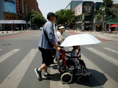 FILE PHOTO: Pedestrians cross a road on a hot day amid an orange alert for heatwave, in Beijing, China June 16, 2023. REUTERS/Florence Lo/File Photo