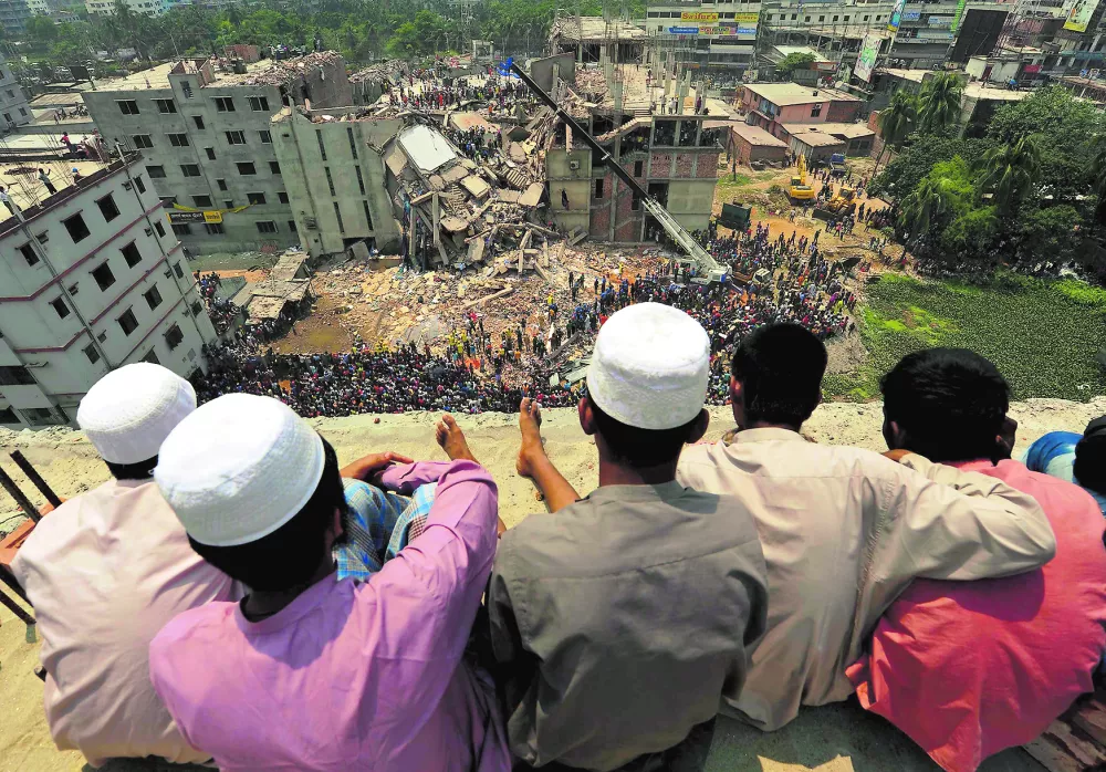 People watch as rescue workers continue their operations at the collapsed Rana Plaza building in Savar, 30 km (19 miles) outside Dhaka April 25, 2013. Survivors from the garment factory that collapsed in Bangladesh killing at least 228 people described on Thursday a deafening bang and tremors before the eight-floor building crashed down under them. REUTERS/Stringer (BANGLADESH - Tags: BUSINESS DISASTER TPX IMAGES OF THE DAY)