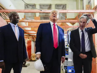 Federal Reserve Chairman Jerome Powell, right, takes off his hard hat as President Donald Trump, center, and Sen. Tim Scott, R-S.C., look at ongoing construction at the Federal Reserve, Thursday, July 24, 2025, in Washington. (AP Photo/Julia Demaree Nikhinson)