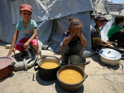 Palestinian children react near pots of food from a charity kitchen, amid a hunger crisis, in Gaza City, July 25, 2025. REUTERS/Dawoud Abu Alkas