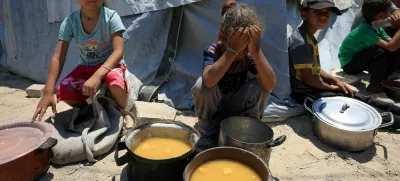 Palestinian children react near pots of food from a charity kitchen, amid a hunger crisis, in Gaza City, July 25, 2025. REUTERS/Dawoud Abu Alkas