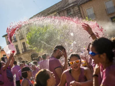 A man pours red wine on revelers during the "Batalla del Vino" (Battle of Wine) in Toro (Zamora), on August 24, 2015. Toro, a small village of Spain known for having Toro wine appellation, celebrated the first battle of wine in the Main Square during the festivities of San Agustin, imitating the wine battle of Haro (La Rioja). Hundreds of people dressed in white cover each other in red wine with water pistols, back-mounted spraying devices, buckets and others. (Photo by Manuel Balles/NurPhoto) (Photo by NurPhoto/NurPhoto via Getty Images)