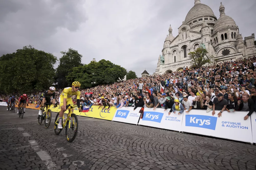 Slovenia's Tadej Pogacar,, wearing the overall leader's yellow jersey, leads riders as they pedal in front of the Sacre Coeur basilica in Montmartre district, during the last stage of the Tour de France cycling race between Mantes-la-Ville and Paris, Sunday, July 27, 2025 in Paris (AP Photo/Thomas Padilla)