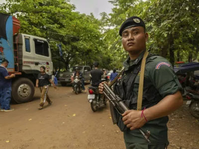 An armed Cambodian National Police officer protects a supply truck at a resettlement camp, established to house thousands of people fleeing the Thailand-Cambodia clash, in Oddar Meanchey, Cambodia, on Sunday, July 27, 2025. (AP Photo/Anton L. Delgado)