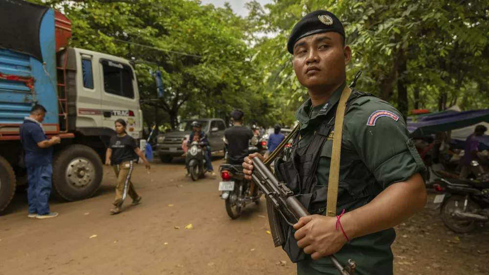 An armed Cambodian National Police officer protects a supply truck at a resettlement camp, established to house thousands of people fleeing the Thailand-Cambodia clash, in Oddar Meanchey, Cambodia, on Sunday, July 27, 2025. (AP Photo/Anton L. Delgado)