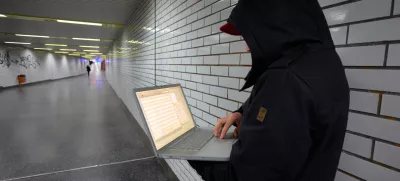 C8JB5H Computer user, hacker, sits conspiratorially with a laptop, in a subway station. Symbol picture, computer-Internet crime.