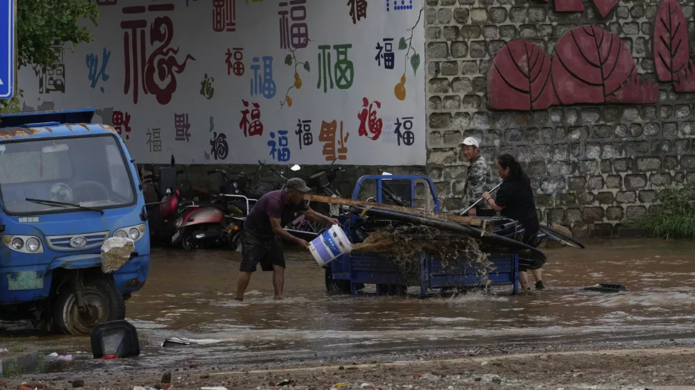 People clean their vehicle in floodwaters after heavy rain in Taishitun Town, Miyun district on the outskirts of Beijing, China, Monday, July 28, 2025. (AP Photo/Mahesh Kumar A.)