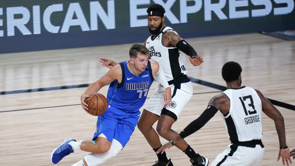 Aug 21, 2020; Lake Buena Vista, Florida, USA; Dallas Mavericks' Luka Doncic (77) drives against Los Angeles Clippers' Marcus Morris Sr., center, and Paul George (13) during the second half in a NBA basketball first round playoff game at AdventHealth Arena. Mandatory Credit: Ashley Landis/Pool Photo-USA TODAY Sports