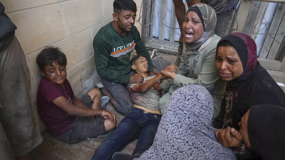 People mourn over the body of a young Palestinian killed while trying to reach trucks carrying humanitarian aid en route to Gaza City, outside the Hamad Al-Qatari Hospital in Beit Lahiya, northern Gaza Strip, Friday, Aug. 1, 2025. (AP Photo/Jehad Alshrafi)