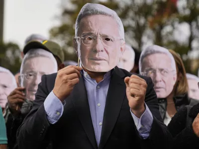 Supporters of former Colombian President Alvaro Uribe hold cutouts of his face outside the court where a verdict is expected in his trial for witness tampering in Bogota, Colombia, July 28, 2025. (AP Photo/Fernando Vergara)