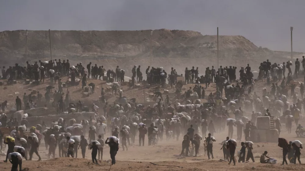 Palestinians carry humanitarian aid packages near a Gaza Humanitarian Foundation distribution center operated by the U.S.-backed organization, in Netzarim, central Gaza Strip, Monday, Aug. 4, 2025. (AP Photo/Abdel Kareem Hana)