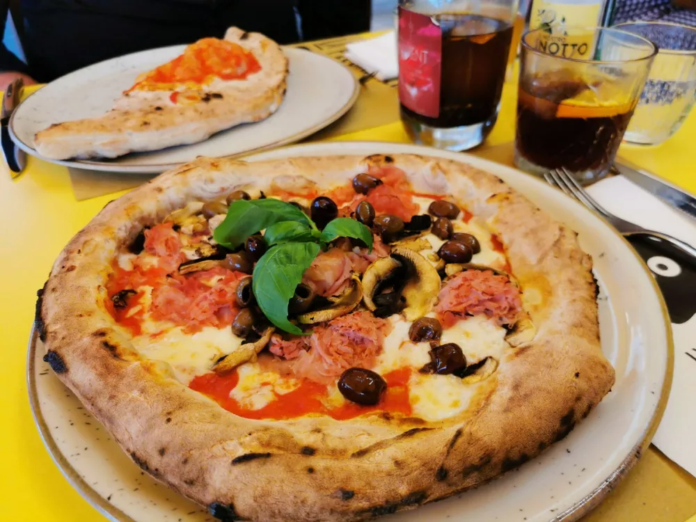 Klasična margherita, v ozadju zaprta calzone. 