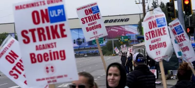 FILE - Boeing workers wave picket signs as they strike after union members voted to reject a contract offer near the company's factory in Everett, Washington, Sept. 15, 2024. (AP Photo/Lindsey Wasson)