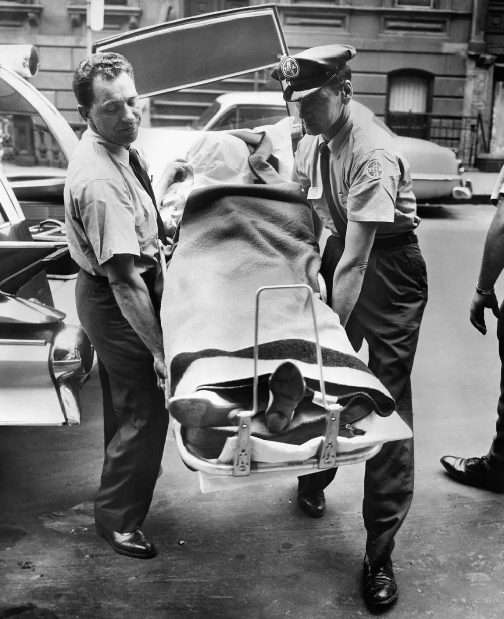 An ambulancer and a policeman paramedics carry the body of American actress Marilyn Monroe out of a mortuary van, on August 05, 1962, after she was discovered dead in her house in Brentwood, Los Angeles, California.,Image: 695688933, License: Rights-managed, Restrictions:, Model Release: no