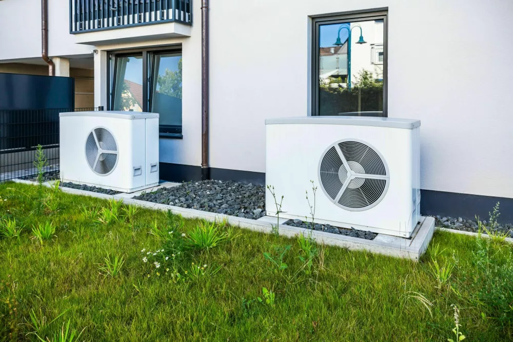2XWNAMH Two air source heat pumps installed outside of new and modern city house, green renewable energy concept of heat pump