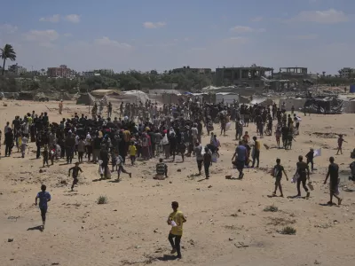 Palestinians rush to collect humanitarian aid airdropped by parachutes into Deir Al-Balah, in the central Gaza Strip, Tuesday, Aug. 5, 2025. (AP Photo/Abdel Kareem Hana)