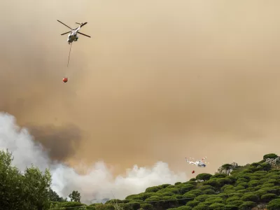 Firefighting helicopters drop water to extinguish a blaze in Torre de la Pe&ntilde;a, southern Spain, Tuesday, Aug. 5, 2025. (Nono Rico/Europa Press via AP)