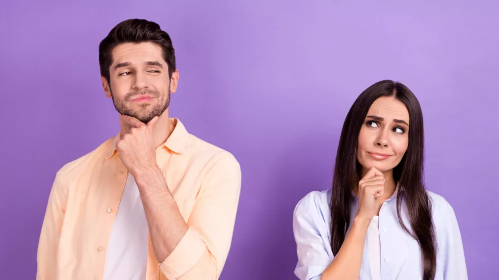 Photo of unsure funny husband wife dressed shirts looking empty space arm chin isolated purple color background. / Foto: Deagreez