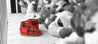 Otroški copatki v zibki v družbi plišastih živali