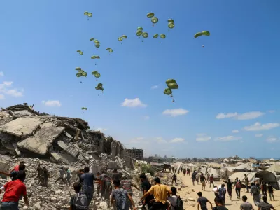 Palestinians run towards parachutes carrying aid packages airdropped over northern Gaza Strip, August 7, 2025. REUTERS/Ebrahim Hajjaj