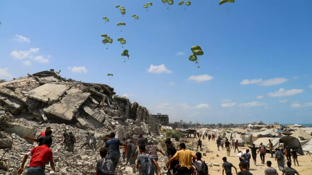 Palestinians run towards parachutes carrying aid packages airdropped over northern Gaza Strip, August 7, 2025. REUTERS/Ebrahim Hajjaj