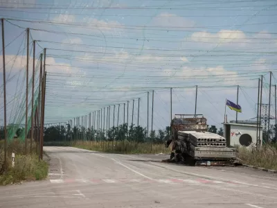 A view shows a burned vehicle and anti-drone nets installed over a road near the frontline town of Dobropillia, amid Russia's attack on Ukraine, in Donetsk region, Ukraine August 10, 2025. REUTERS/Oleksandr Ratushniak