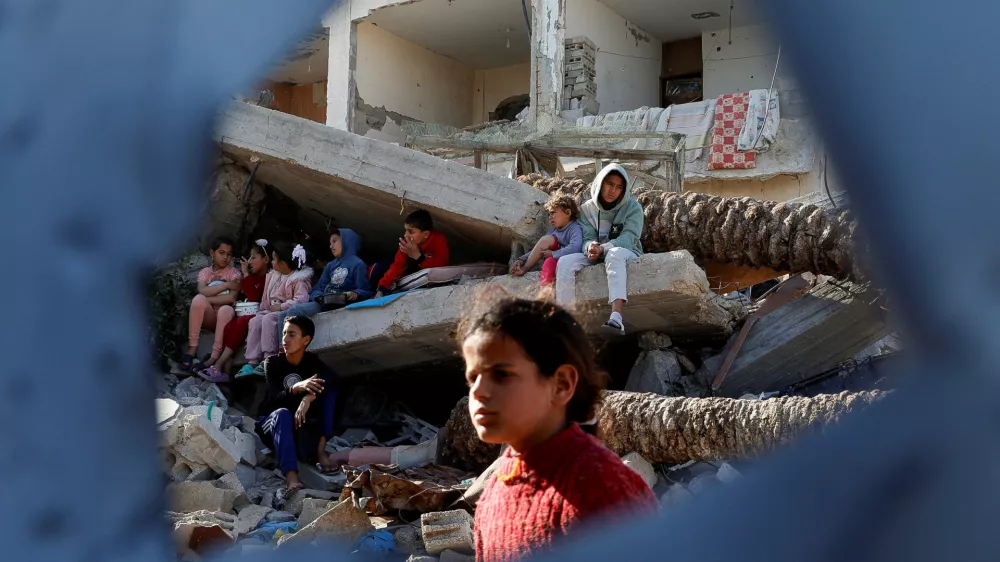 Palestinian children sit on rubble as they wait to receive food cooked by a charity kitchen, during the Muslim holy month of Ramadan, in Rafah, in the southern Gaza Strip, March 13, 2025. REUTERS/Hatem Khaled