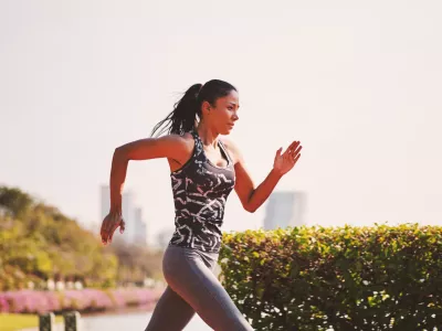 Sport girl in sporty outfit running at the lane in the park