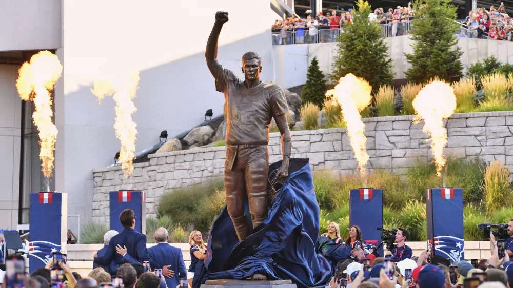A bronze statue of former New England Patriots quarterback Tom Brady is unveiled in Patriot Place Plaza before an NFL preseason football game between the Washington Commanders and the New England Patriots Friday, Aug. 8, 2025, in Foxborough, Mass. (AP Photo/Steven Senne)