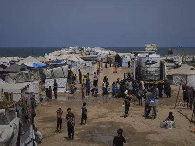 Displaced Palestinians gather to collect water from a truck during a heat wave at a makeshift tent camp in Khan Younis, Gaza Strip, Wednesday, Aug. 13, 2025. (AP Photo/Abdel Kareem Hana)