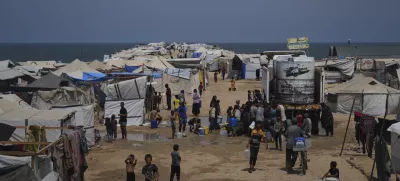 Displaced Palestinians gather to collect water from a truck during a heat wave at a makeshift tent camp in Khan Younis, Gaza Strip, Wednesday, Aug. 13, 2025. (AP Photo/Abdel Kareem Hana)