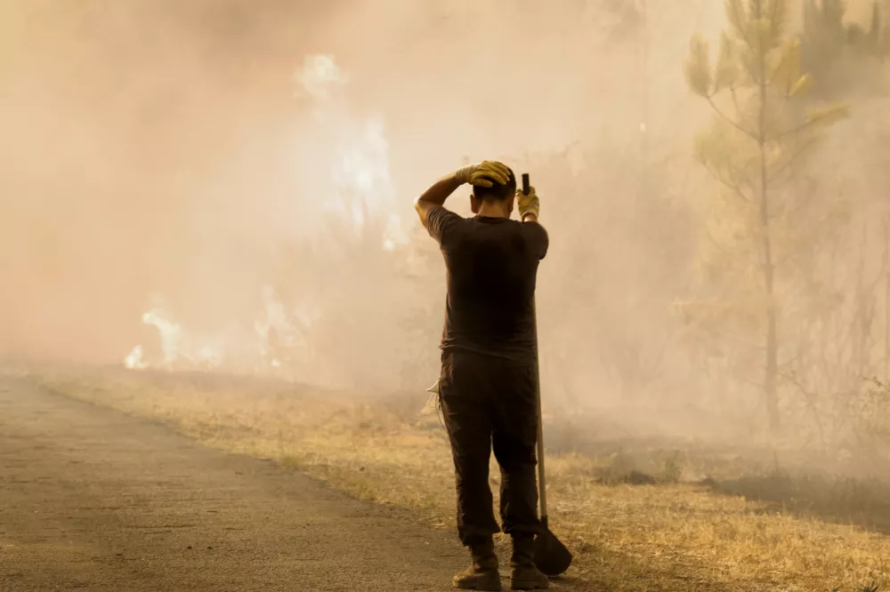 A volunteer reacts in front of a wildfire in Larouco, northwestern Spain, Wednesday, Aug. 13, 2025. (AP Photo/Lalo R. Villar)