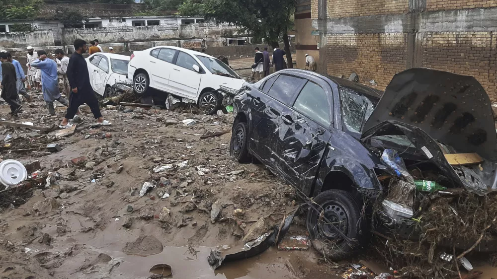 Local residents look damaged cars trapped in a mud following flash flooding due to heavy rains at a neighbourhood of Mingora, the main town of Swat Valley, northwestern Pakistan, Friday, Aug. 15, 2025. (AP Photo/Naveed Ali)