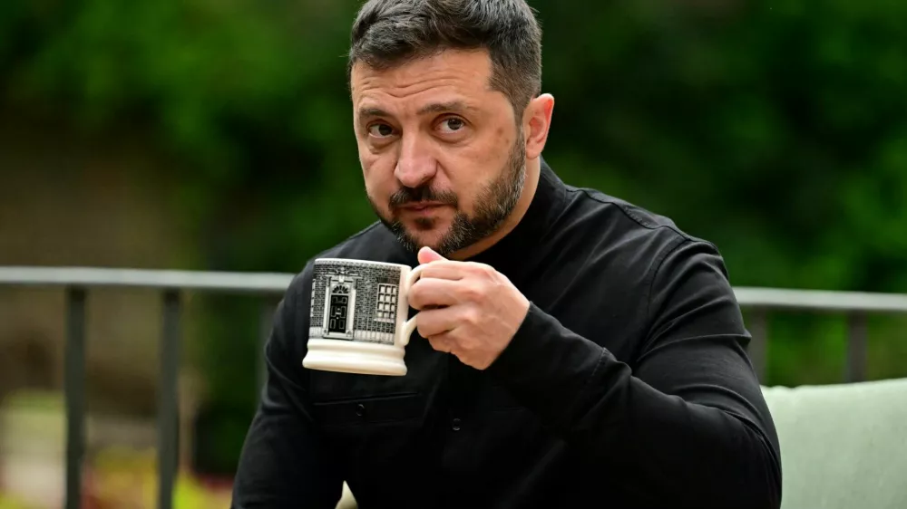 Ukraine's President Volodymyr Zelenskiy drinks from a Downing Street-themed mug as he sits with Britain's Prime Minister Keir Starmer (unseen) in the garden of 10 Downing Street in central London, Britain August 14, 2025. BEN STANSALL/Pool via REUTERS