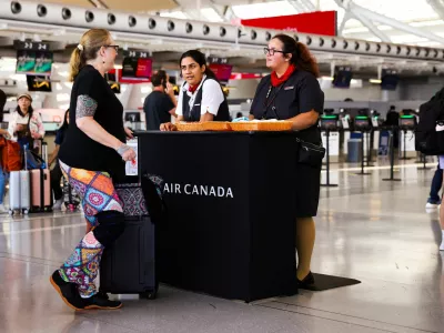 Air Canada workers speak with a passenger at a kiosk to deal with flight disruptions, ahead of a potential strike by flight attendants of the airline, at the Toronto Pearson International Airport in Mississauga, Ontario, Canada, August 15, 2025. REUTERS/Cole Burston