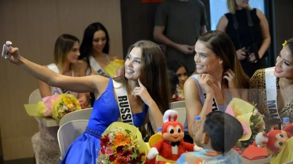 (From L to R) Miss Universe contestants Kseniya Alexandrova of Russia, Nicky Opheij of the Netherlands and Samantha James of Malaysia take a selfie with children from an orphanage during a visit to a popular fast food restaurant in Manila on December 7, 2017. Miss Universe Demi-Leigh Nel-Peters of South Africa and other pageant contestants are in Manila for a visit after the contest in Las Vegas last month.,Fotografija:357133851, Licenca:Rights-managed, Omejitve:, Model izdaje:no