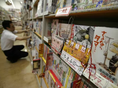 A Japanese Manga "Ichi Efu" (2nd R), which centres on workers at the Fukushima Daiichi nuclear plant, is seen on a bookshelf as a staff adjusts manga comics at a bookstore in Tokyo June 23, 2014. Japanese farmers in Fukushima try to convince sceptical visitors that their crops are safe from radiation. Blood trickles from the nose of a reporter who visits the area. These are just two of the tales from the aftermath of the world's worst nuclear disaster in 25 years - as told by manga, Japan's ubiquitous comics for adults and teens, which have taken up Fukushima on an unprecedented scale even as Japanese film largely avoids the topic. Picture taken June 23, 2014. REUTERS/Yuya Shino (JAPAN - Tags: SOCIETY DISASTER) / Foto: Yuya Shino