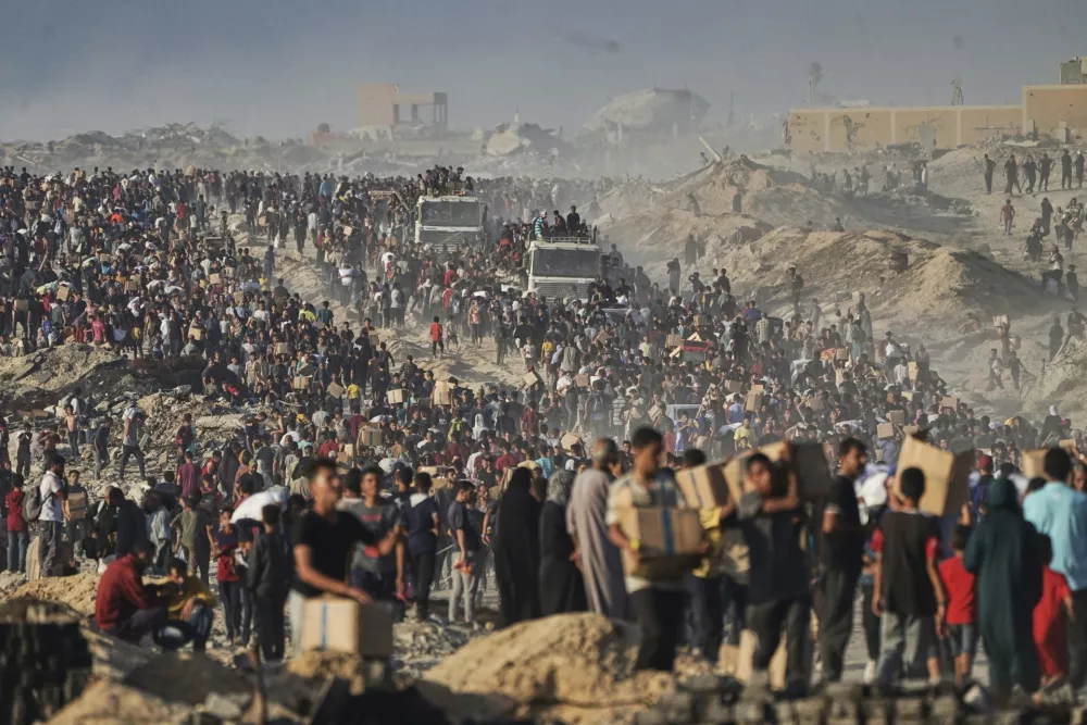 Palestinians carry sacks and boxes of food and humanitarian aid, unloaded from a World Food Program convoy in the northern Gaza Strip, June 16, 2025. (AP Photo/Jehad Alshrafi)
