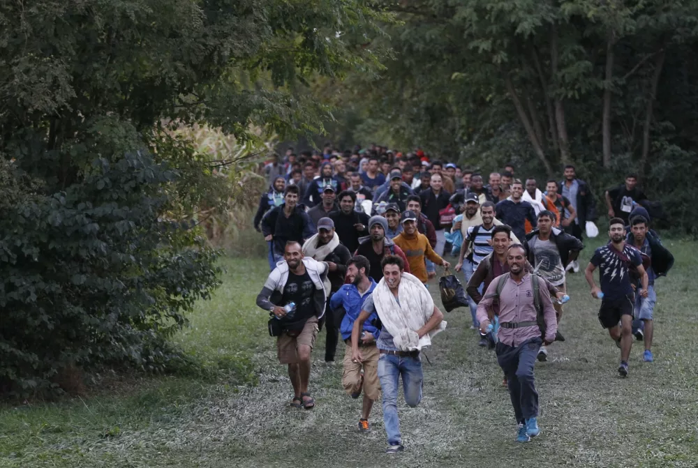FILE - In this Sept. 20, 2016 file photo, migrants run as they cross the border from Croatia near the village of Zakany, Hungary. In a year when more than a million people arrived on European shores, UNHCR said Monday, June 20, 2016 that continued conflicts and persecution in places like Syria and Afghanistan fueled a nearly 10-percent increase in the total number of refugees and internally displaced people in 2015.((AP Photo/Petr David Josek, File)