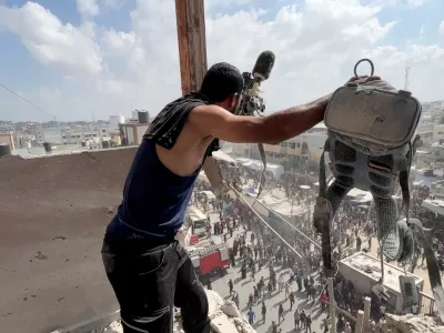 A man reacts as he holds the equipment used by Palestinian cameraman Hussam al-Masri, who was a contractor for Reuters, at the site where he was killed along with other journalists and people in Israeli strikes on Nasser hospital, in Khan Younis in the southern Gaza Strip, in this still image taken from a video shot by Reuters contractor Hatem Khaled, who was wounded shortly afterwards in another strike while he was filming the site, August 25, 2025. REUTERS/Hatem Khaled   TPX IMAGES OF THE DAY