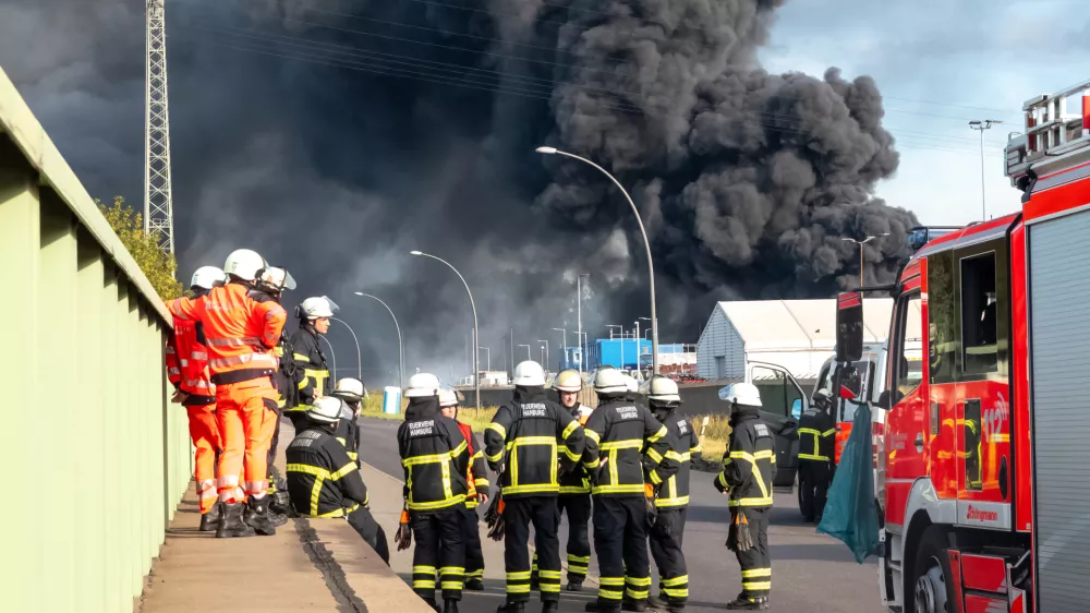 25 August 2025, Hamburg: Emergency services prepare for their deployment to extinguish a major fire in a warehouse in Hamburg. A fire has broken out in a warehouse in the Port of Hamburg, causing a major motorway nearby to be closed. Photo: Bodo Marks/dpa
