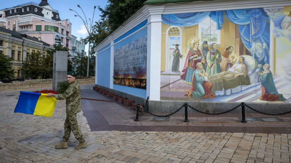 A soldier carries a Ukrainian national flag outside St. Michael's Golden-Domed Monastery, amid Russia's attack on Ukraine, in Kyiv, Ukraine August 25, 2025. REUTERS/Thomas Peter