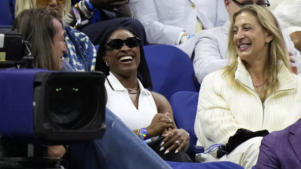 Gymnast Simone Biles, center, reacts after Coco Gauff, of the United States, mentioned her following Gauff's match against Donna Vekic, of Croatia, during the second round of the U.S. Open tennis championships, Thursday, Aug. 28, 2025, in New York. (AP Photo/Frank Franklin II)