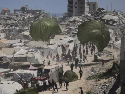Palestinians rush to collect humanitarian aid airdropped by parachutes into Gaza City, northern Gaza Strip, Aug. 7, 2025. (AP Photo/Jehad Alshrafi)